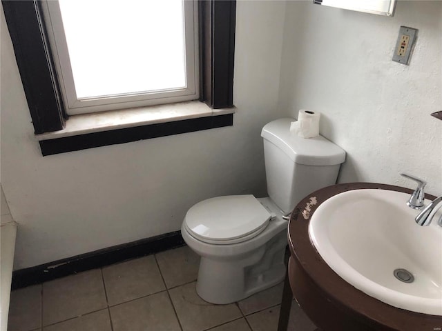 bathroom with a sink, baseboards, toilet, and tile patterned flooring