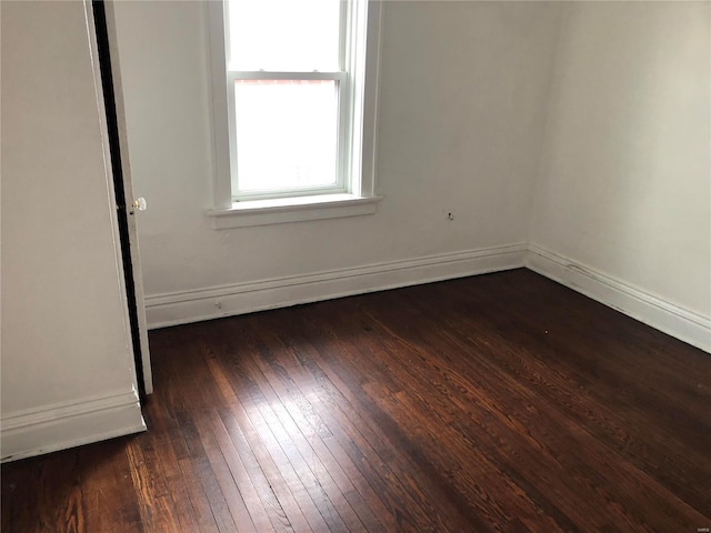 spare room with baseboards and dark wood-style floors