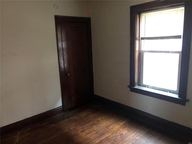 empty room featuring dark wood-type flooring and baseboards