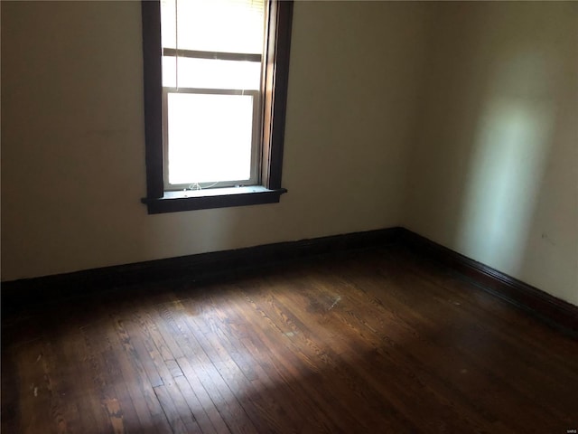 spare room with baseboards and hardwood / wood-style floors