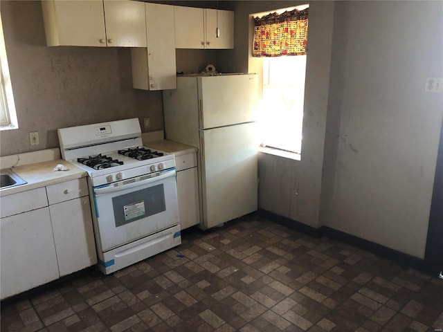 kitchen featuring white appliances, white cabinetry, light countertops, and brick floor