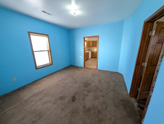 unfurnished bedroom featuring carpet floors, visible vents, a textured ceiling, and ensuite bath