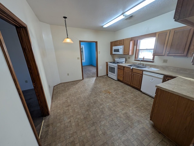 kitchen with pendant lighting, light countertops, visible vents, a sink, and white appliances