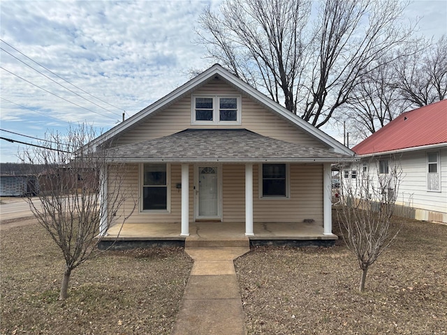 bungalow-style house featuring a porch and roof with shingles