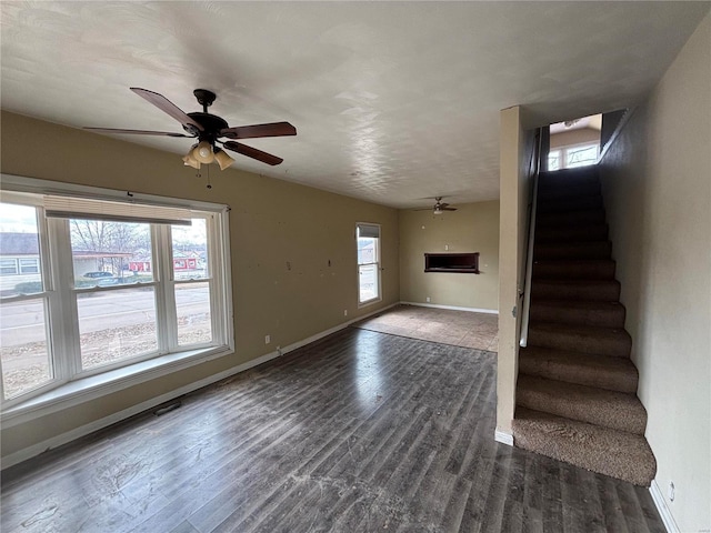 unfurnished living room with ceiling fan, stairs, baseboards, and wood finished floors