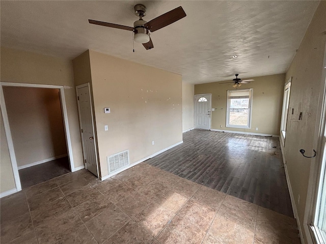 unfurnished living room featuring visible vents, ceiling fan, baseboards, and wood finished floors