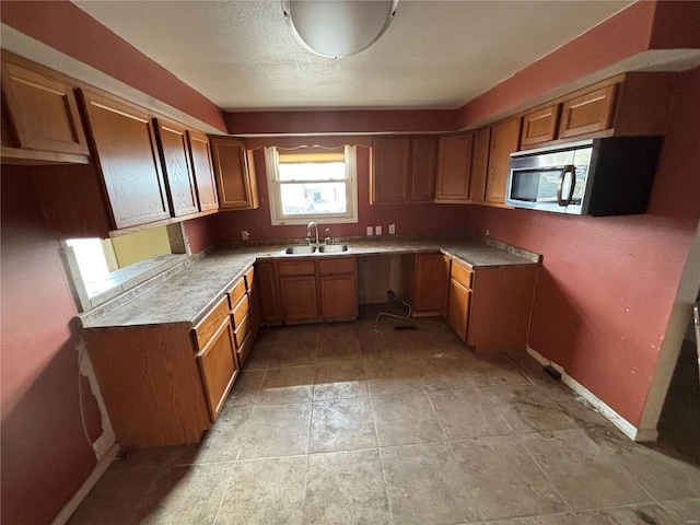 kitchen with stainless steel microwave, brown cabinets, and a sink