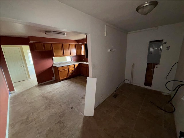 kitchen with electric panel, brown cabinets, and light countertops