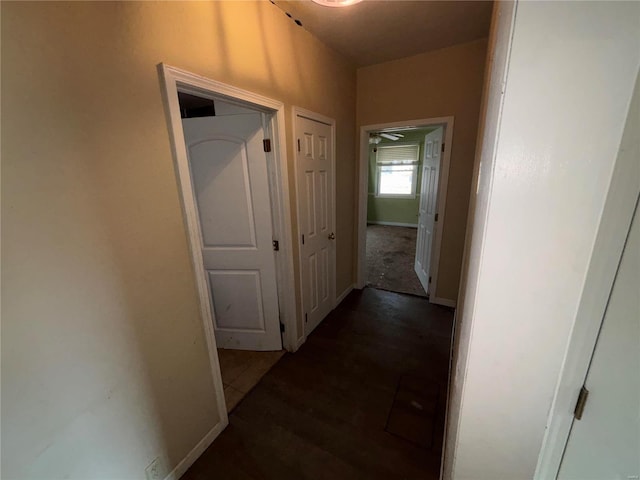 corridor featuring baseboards and wood finished floors