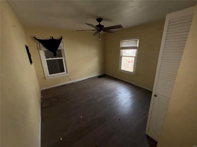 unfurnished bedroom with ceiling fan, dark wood-style flooring, and baseboards