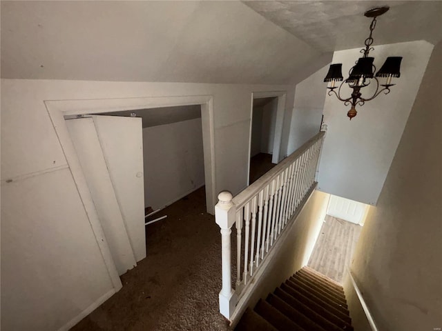 stairway featuring lofted ceiling and a notable chandelier