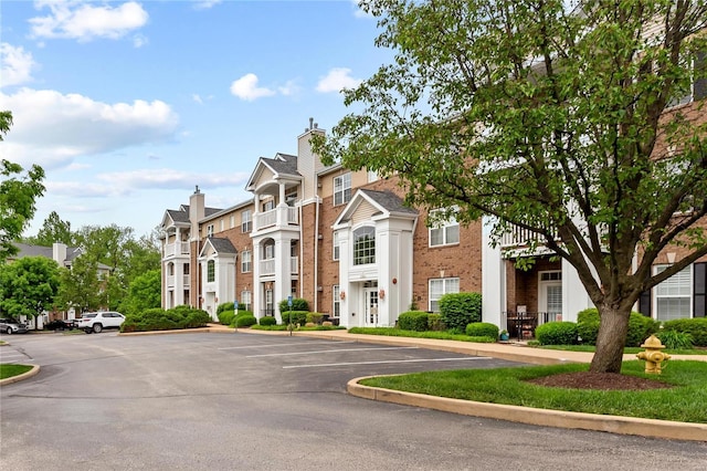 view of front facade featuring uncovered parking, a residential view, and brick siding