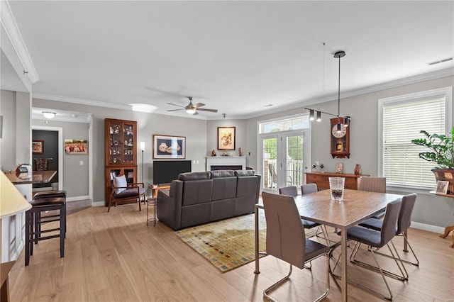 dining room with light wood-type flooring, a fireplace, visible vents, and crown molding