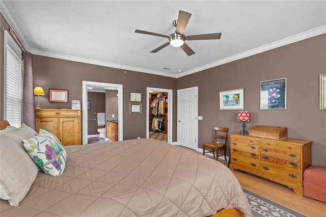 bedroom with a walk in closet, crown molding, a closet, ceiling fan, and wood finished floors