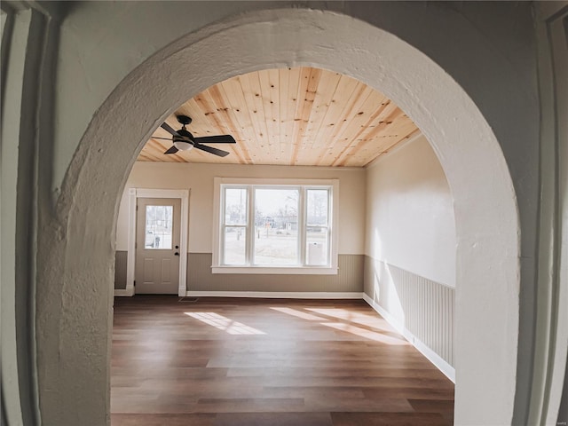 foyer entrance featuring arched walkways, wooden ceiling, wainscoting, and wood finished floors