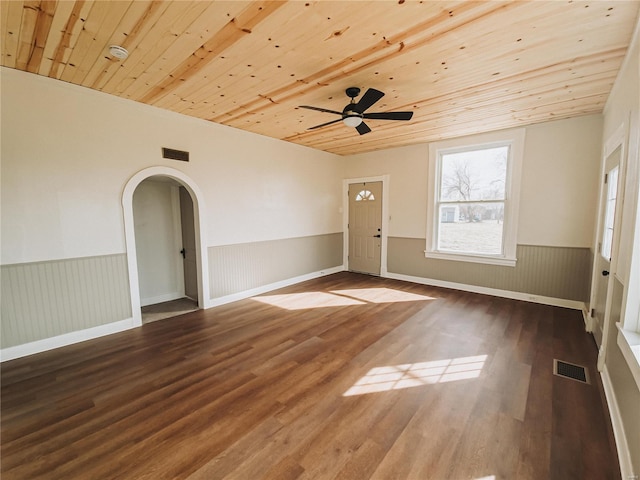 unfurnished room with arched walkways, wood finished floors, visible vents, wood ceiling, and wainscoting