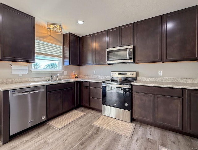 kitchen featuring stainless steel appliances, light countertops, a sink, and dark brown cabinets