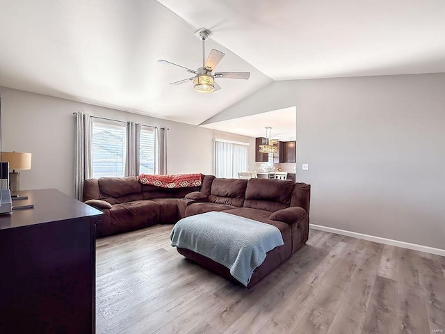 living area featuring light wood-type flooring, baseboards, a ceiling fan, and lofted ceiling