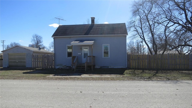 view of front facade featuring roof with shingles, a chimney, and fence