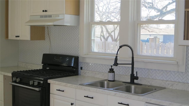 kitchen with black gas range oven, under cabinet range hood, light countertops, and a sink