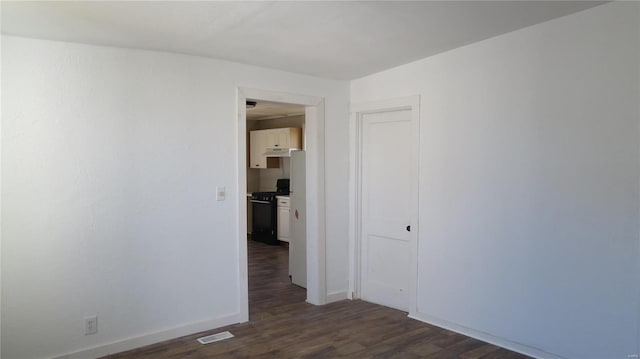 empty room featuring dark wood-style floors, baseboards, and visible vents