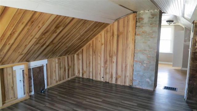 bonus room featuring visible vents, vaulted ceiling, wood walls, and wood finished floors