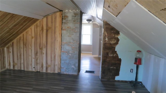 additional living space with lofted ceiling, wood walls, visible vents, and wood finished floors