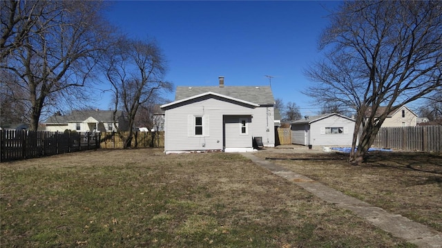 rear view of house featuring a fenced backyard, a yard, and an outdoor structure