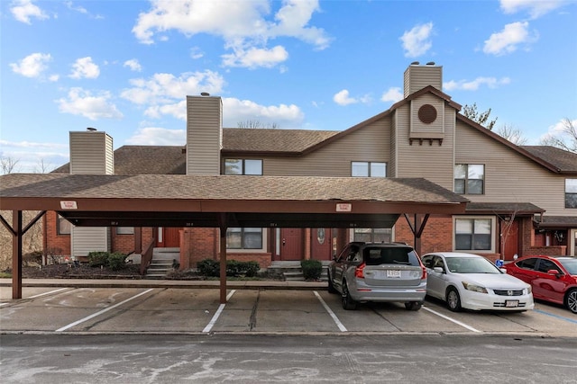 view of building exterior featuring covered and uncovered parking