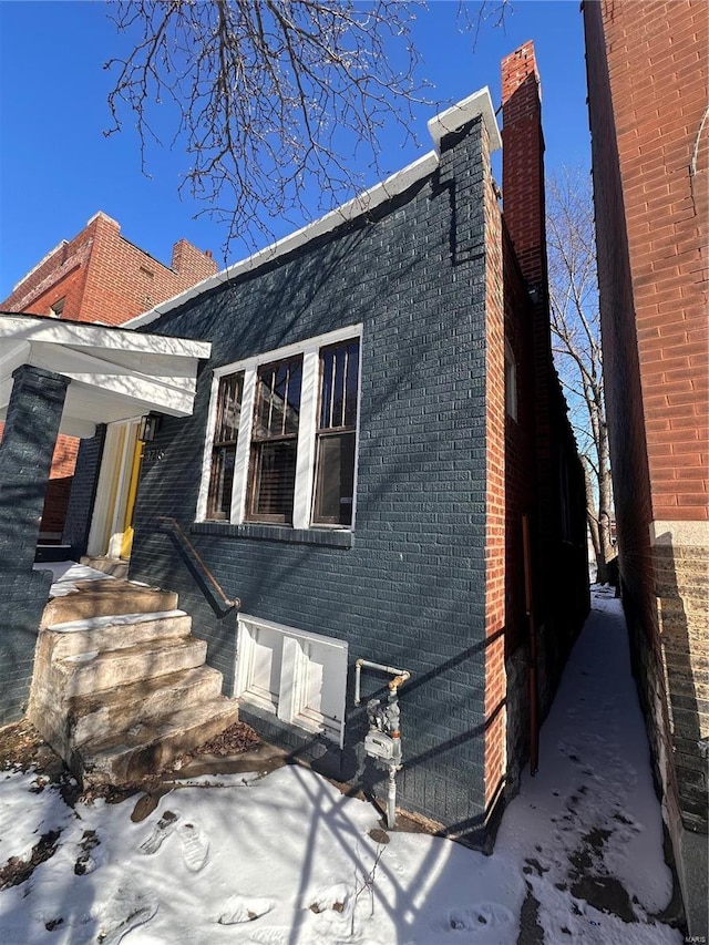 view of front of home featuring brick siding and a chimney