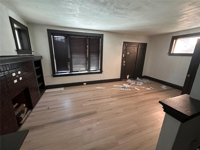 unfurnished living room featuring a textured ceiling and light wood-type flooring