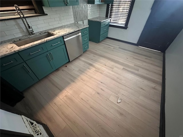 kitchen featuring tasteful backsplash, light wood-style flooring, stainless steel dishwasher, a sink, and green cabinetry