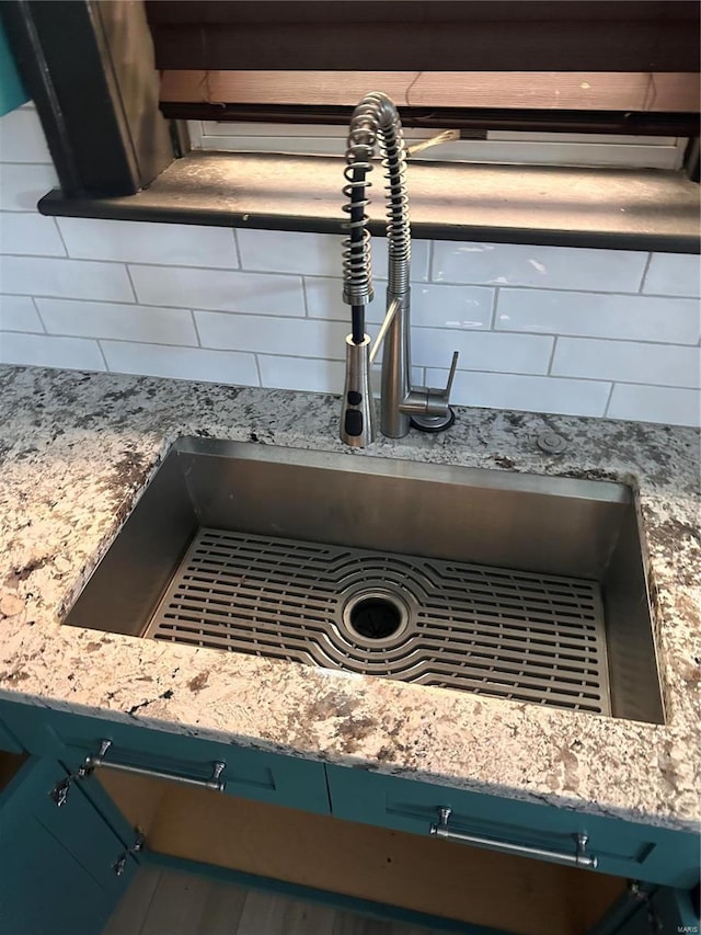 room details featuring blue cabinets, a sink, and decorative backsplash