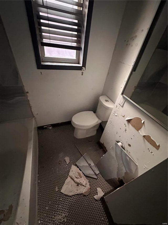 bathroom featuring a washtub, tile patterned flooring, and toilet