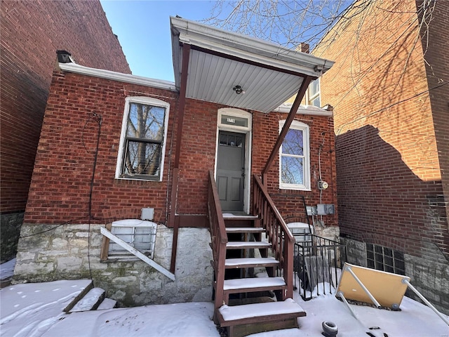 snow covered property entrance with brick siding