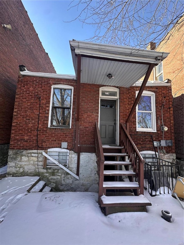 snow covered property entrance with brick siding