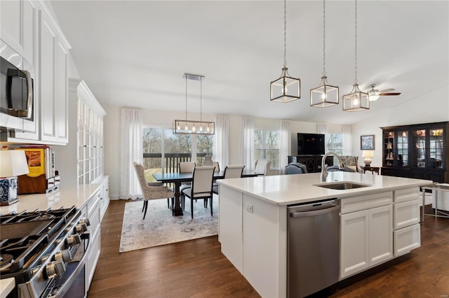 kitchen featuring dark wood-type flooring, open floor plan, light countertops, appliances with stainless steel finishes, and a sink