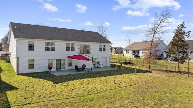 rear view of house featuring a patio, a yard, fence, and a shingled roof