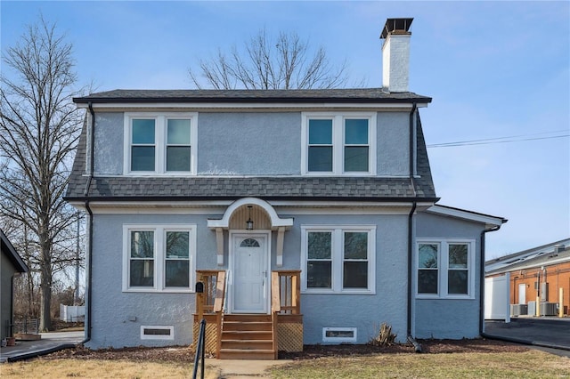 view of front of home featuring roof with shingles, a chimney, and stucco siding