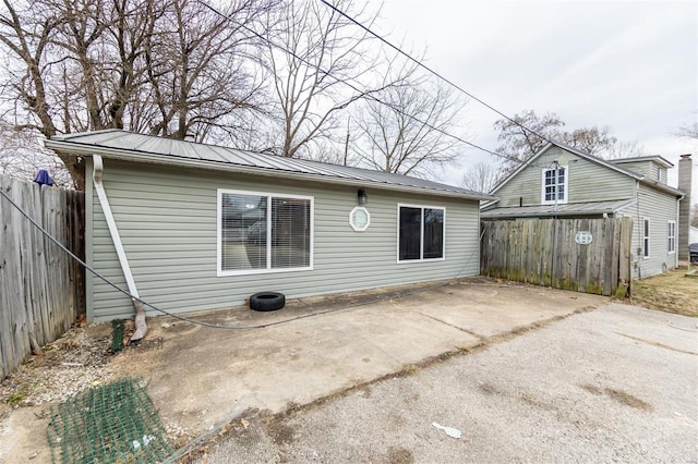 rear view of property featuring metal roof, a patio area, and fence