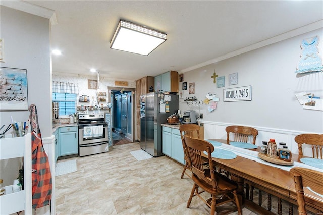 kitchen featuring a wainscoted wall, stainless steel appliances, light countertops, blue cabinetry, and crown molding