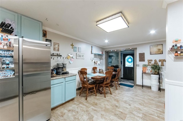 kitchen with light countertops, ornamental molding, blue cabinetry, wainscoting, and freestanding refrigerator