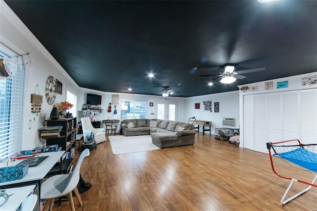 living area featuring ceiling fan, ornamental molding, a wall unit AC, and wood finished floors