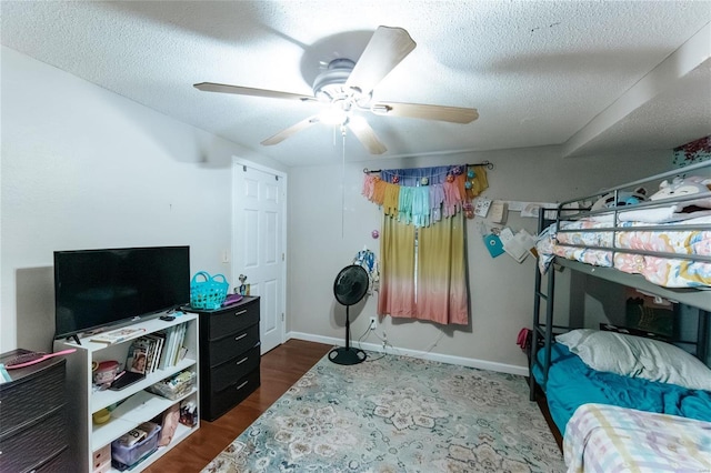 bedroom with dark wood-style floors, ceiling fan, a textured ceiling, and baseboards