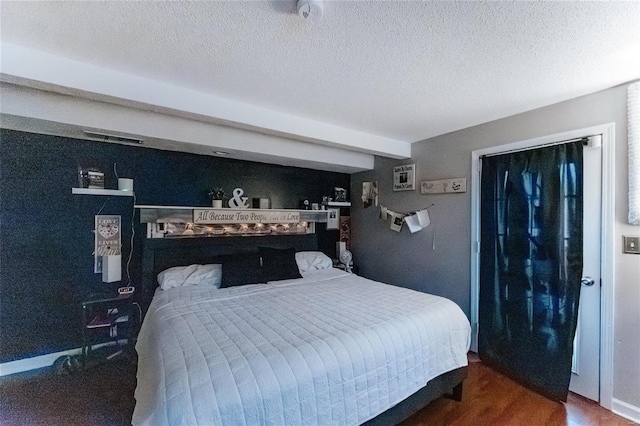 bedroom featuring a textured ceiling, baseboards, and wood finished floors