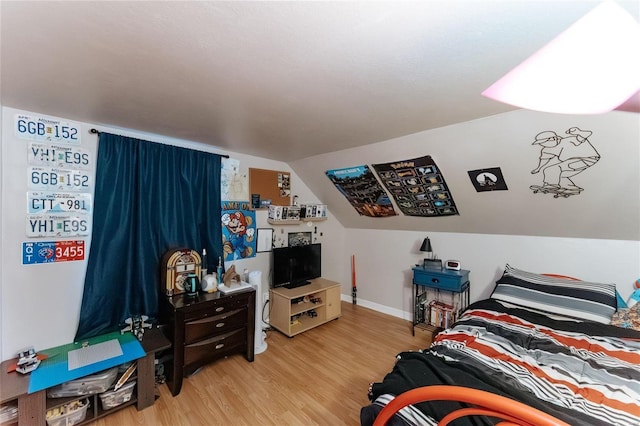 bedroom with vaulted ceiling, baseboards, and wood finished floors