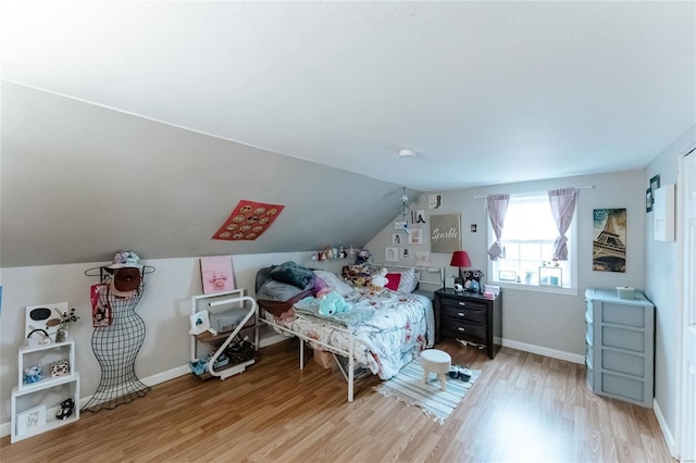 bedroom featuring baseboards, vaulted ceiling, and wood finished floors