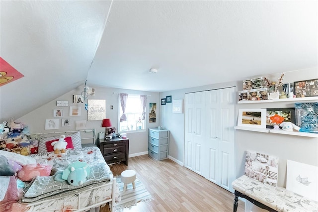 bedroom with a closet, baseboards, vaulted ceiling, and wood finished floors