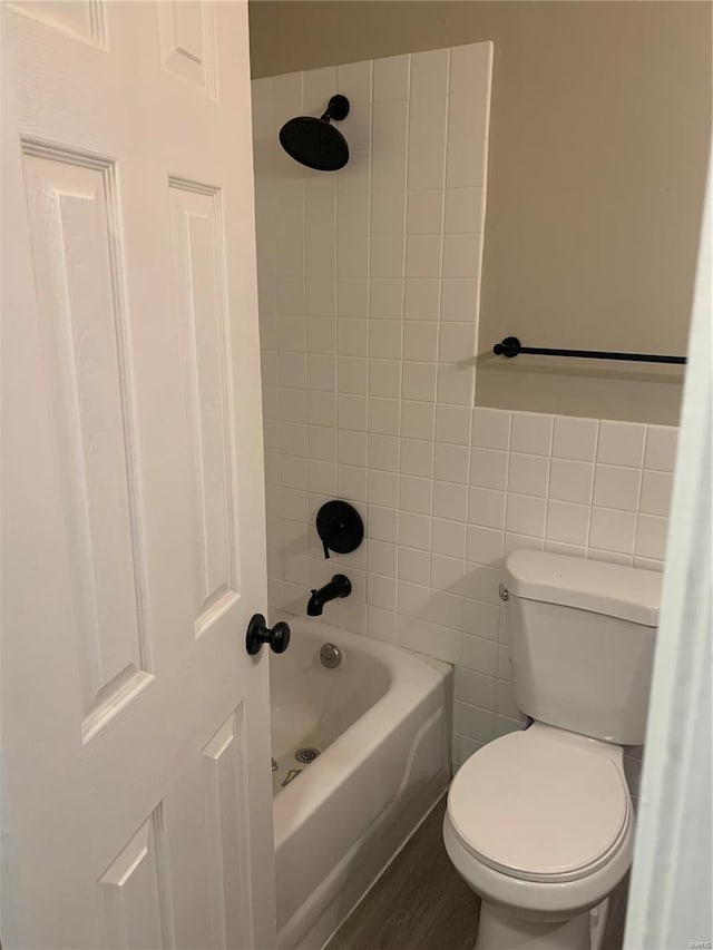 bathroom with tub / shower combination, wood finished floors, toilet, and tile walls