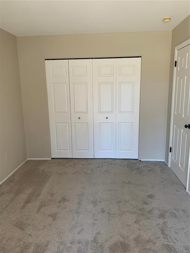 unfurnished bedroom featuring carpet floors, baseboards, and a closet